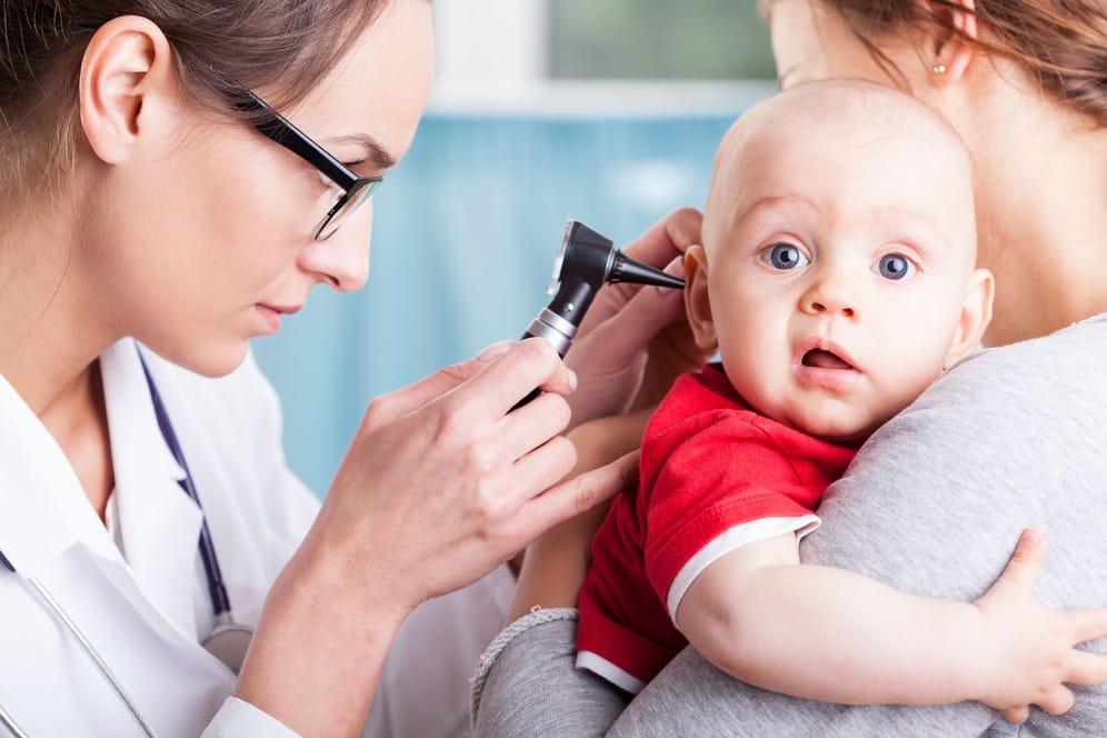 Ohrenärztin untersucht ein Baby auf dem Arm der Mutter