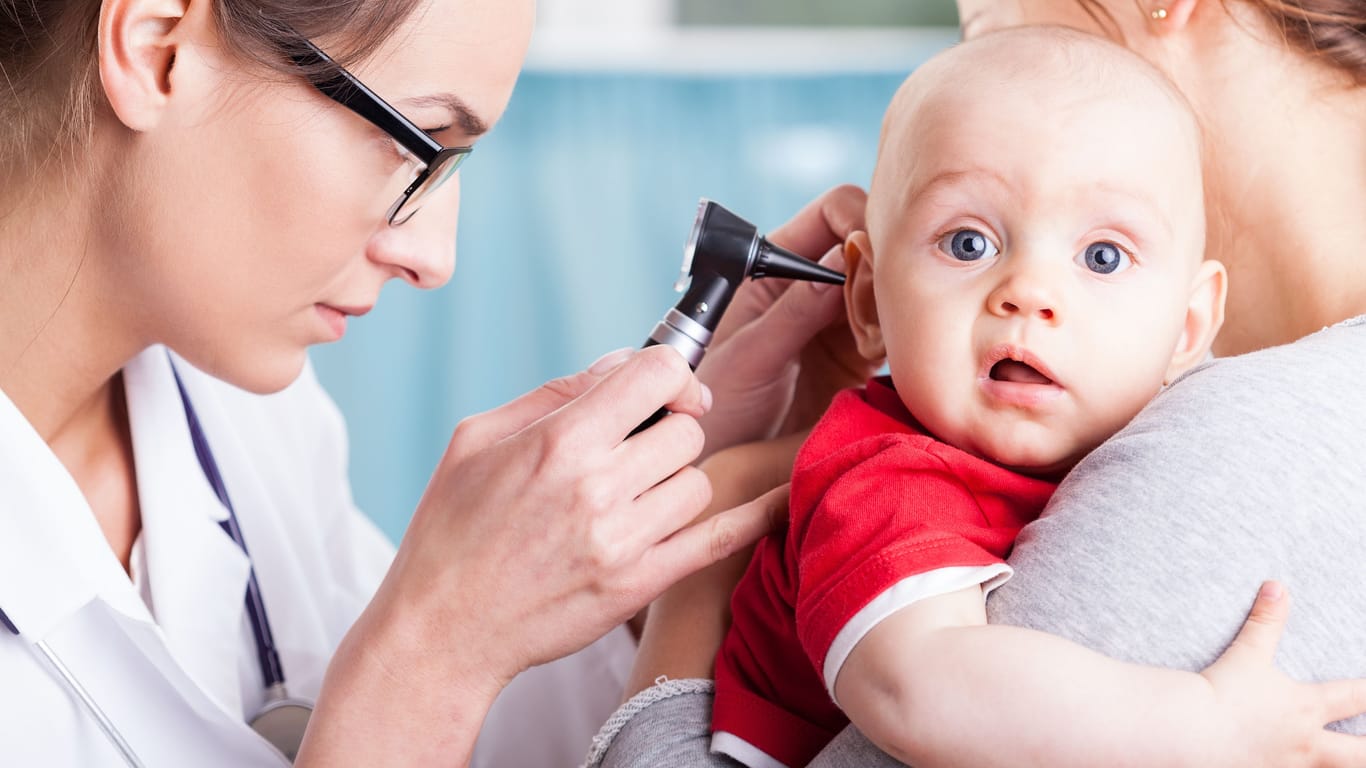 Ohrenärztin untersucht ein Baby auf dem Arm der Mutter