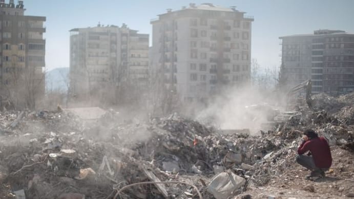 Ein Mann sitzt neben seinem eingestürzten Haus in Kharamanmaras: Das Beben hat in der Türkei mindestens 105.000 Gebäude vollständig oder teilweise zerstört.