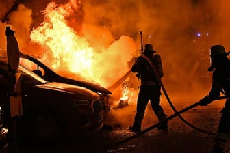 Der Wagen steht in Flammen: Die Feuerwehr kann ein Übergreifen des Brandes auf andere Autos und ein Gebäude verhindern.