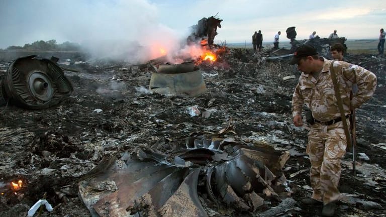 Menschen gehen durch die Trümmer an der Absturzstelle des Passagierflugzeugs MH17.