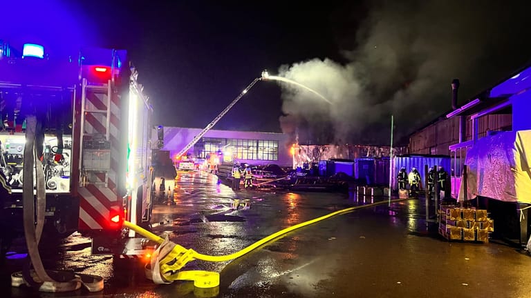 Feuerwehrleute stehen zusammen, um den Einsatz zu besprechen: Eine Lagerhalle stand am Mittwoch in Flammen.