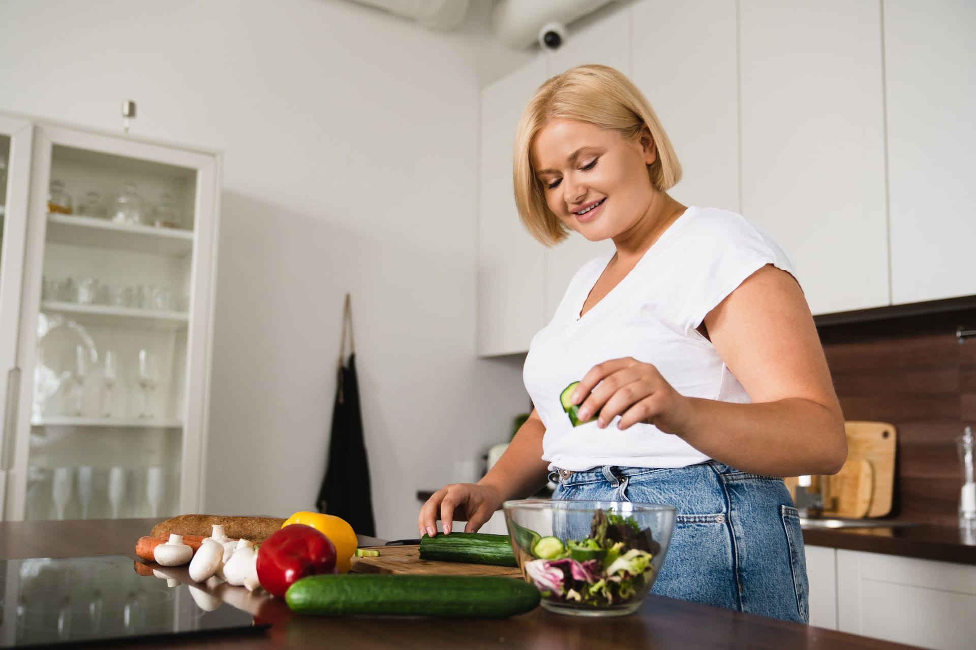 Junge, übergewichtige Frau bereitet einen Salat zu