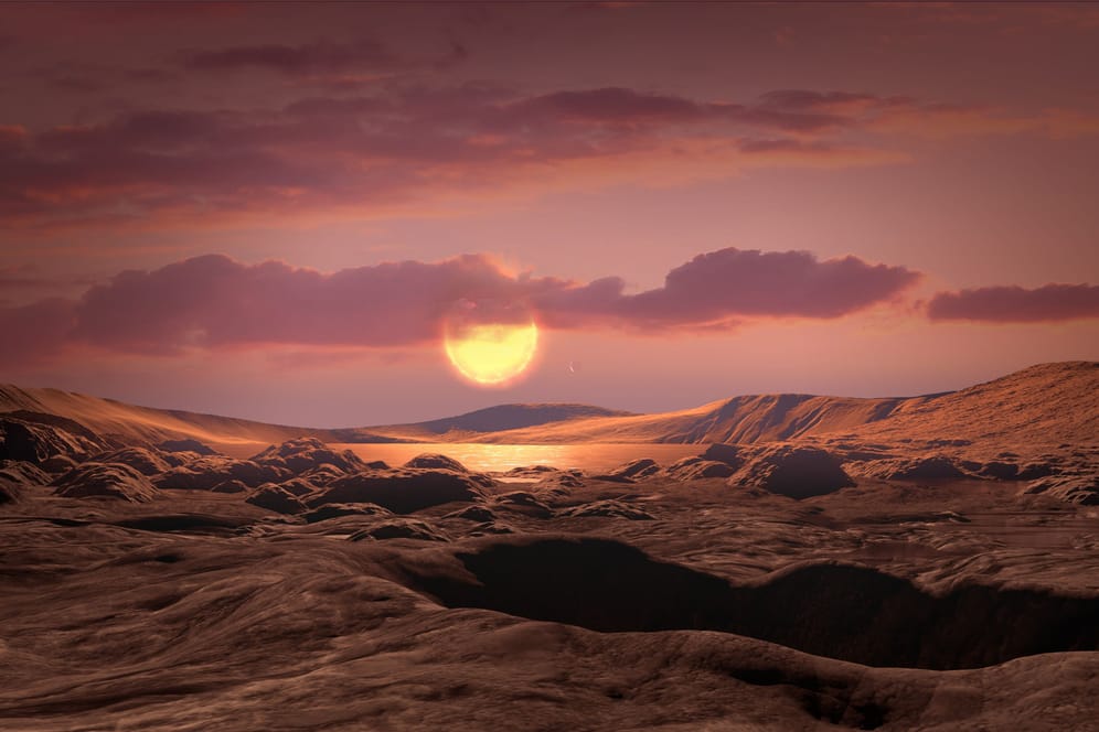 Die Sonne "Wolf 1069" vom Exoplaneten "Wolf 1069 b" aus gesehen: So stellt sich ein Künstler die Oberfläche des Planeten und den Blick auf seinen Stern vor.