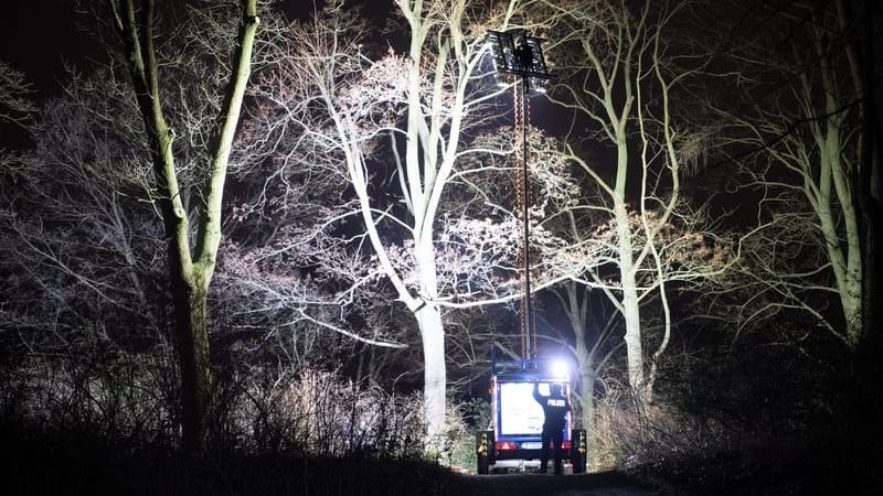 Polizisten beleuchten im Dunkeln den Park: Eine Mordkommission ermittelt.