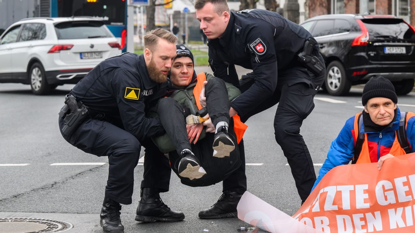 Polizisten tragen zuvor am Asphalt festgeklebte Aktivisten der Gruppierung "Letzte Generation" in Hannover von der Straße (Archivbild): Für solche Einsätze sollen die Aktivisten künftig zahlen.