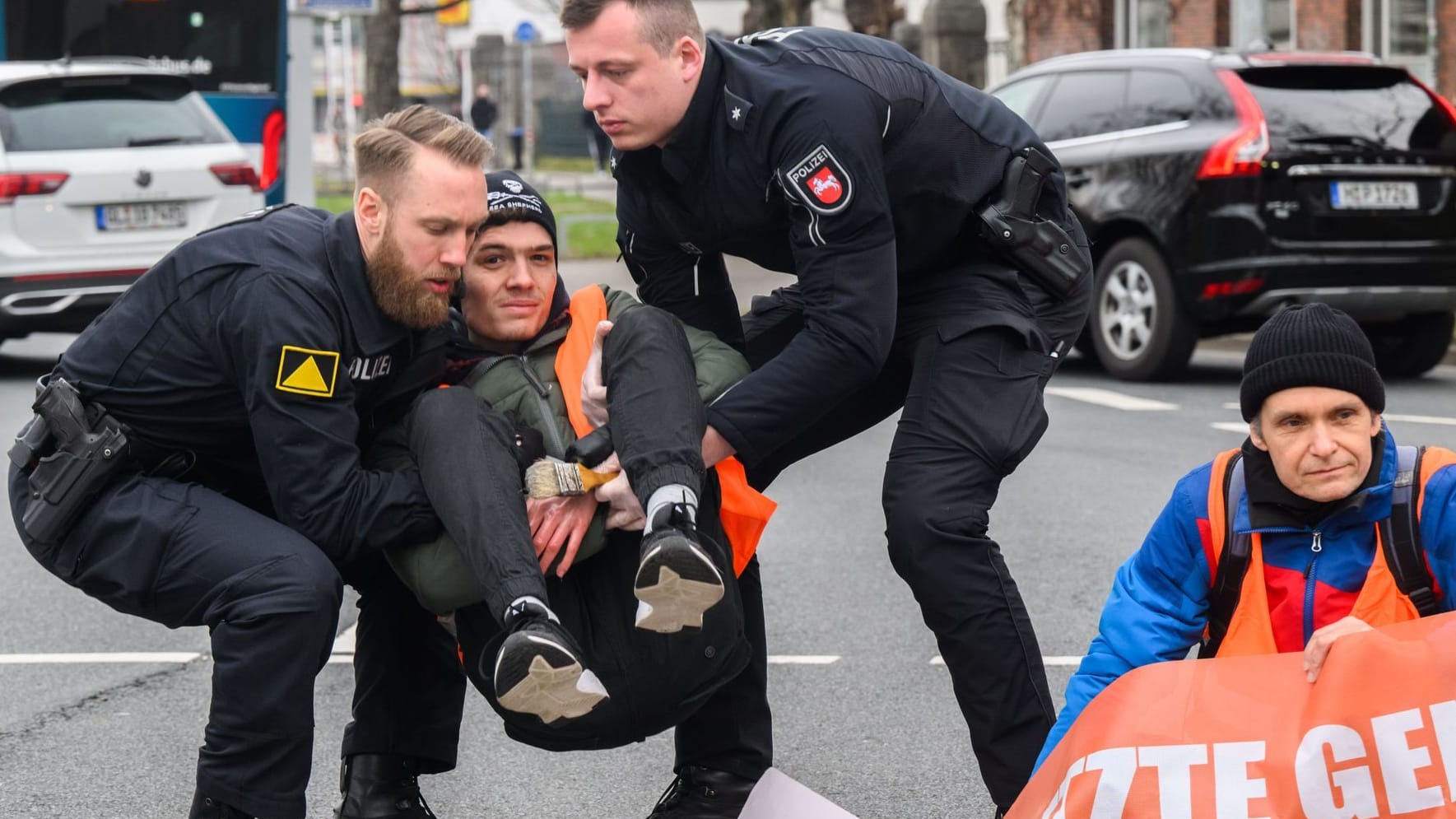 Polizisten tragen zuvor am Asphalt festgeklebte Aktivisten der Gruppierung "Letzte Generation" in Hannover von der Straße (Archivbild): Für solche Einsätze sollen die Aktivisten künftig zahlen.