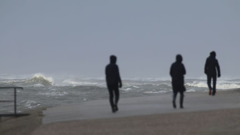 Spaziergänger gehen an der aufgepeitschten Nordsee auf Norderney entlang (Symbolbild): Der Winter im Norden zeigt sich von seiner windigen Seite.
