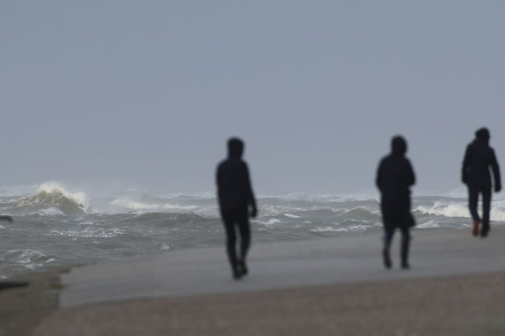 Spaziergänger gehen an der aufgepeitschten Nordsee auf Norderney entlang (Symbolbild): Der Winter im Norden zeigt sich von seiner windigen Seite.