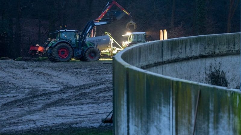 Ein Landwirt und Helfer versuchen, die ausgelaufene Gülle vom Feld zu beseitigen. Ein Landwirt und Helfer versuchen, die ausgelaufene Gülle vom Feld zu beseitigen.