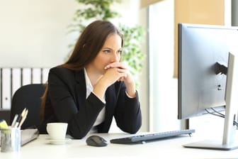 Junge Frau sitzt zögernd vorm Computer (Symbolbild): Wer den Weg an die Börse scheut, lässt sich einiges an Geld entgehen.