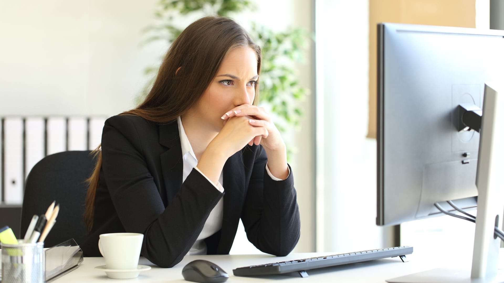 Junge Frau sitzt zögernd vorm Computer (Symbolbild): Wer den Weg an die Börse scheut, lässt sich einiges an Geld entgehen.