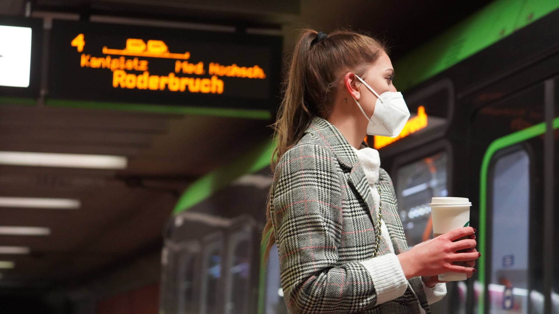 Eine Frau mit einer Maske vor einer einfahrenden Stadtbahn (Archivbild): In Hannover fällt am Donnerstag die Maskenpflicht im GVH.