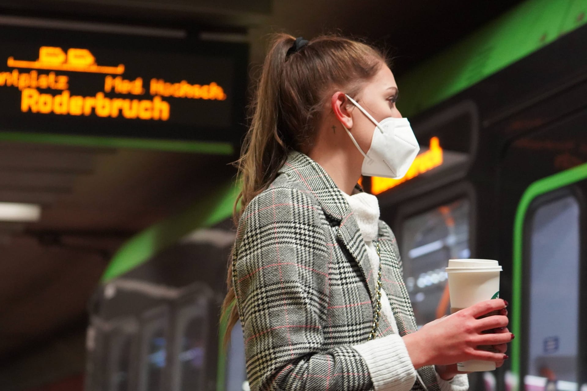 Eine Frau mit einer Maske vor einer einfahrenden Stadtbahn (Archivbild): In Hannover fällt am Donnerstag die Maskenpflicht im GVH.