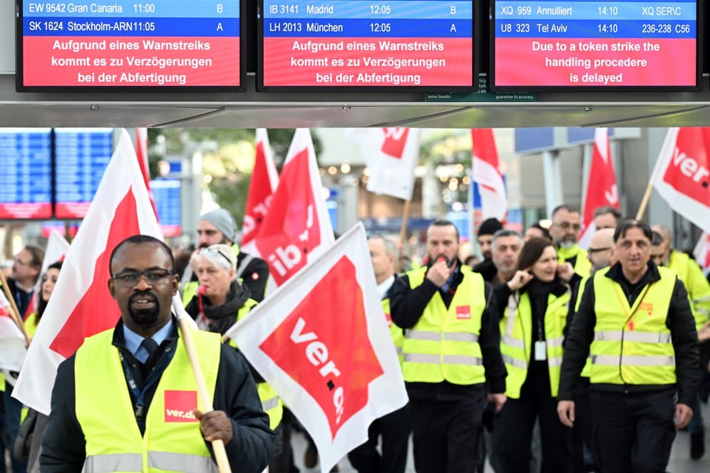 Düsseldorf: Streikende Flughafen-Mitarbeiter stehen mit Verdi-Flaggen im Terminal des Flughafens.