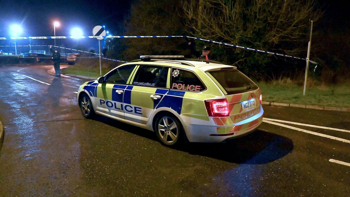 Ein Polizeiwagen steht an einer Absperrung nahe dem Tatort in Nordirland.