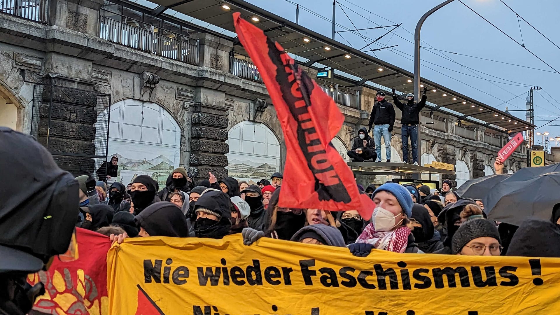 Gegendemo in Dresden: Einzelne Personen auf einer Haltestelle der Straßenbahn.