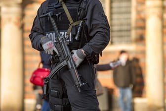 Ein Polizeibeamter mit Schusswaffe (Symbolbild): In Berlin wurde eine Tür gesprengt.