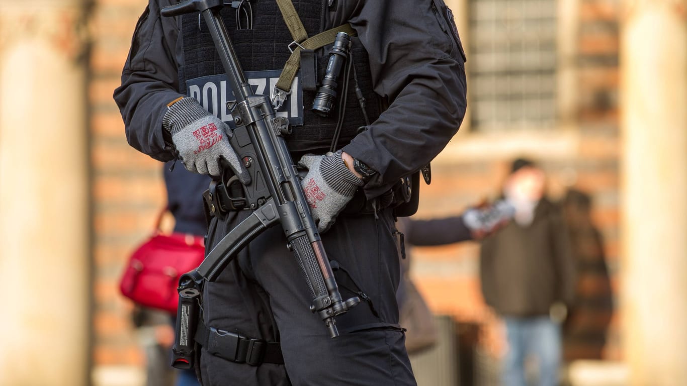 Ein Polizeibeamter mit Schusswaffe (Symbolbild): In Berlin wurde eine Tür gesprengt.