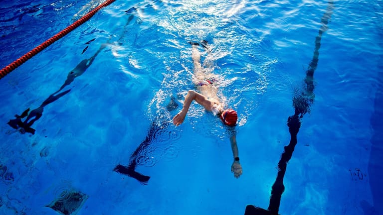 Eine Frau schwimmt durch das Becken eines Hallenbades (Symbolfoto): Der Appell, Energie zu sparen, gilt laut Bäderland weiterhin.