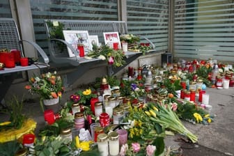 Kerzen und Blumen stehen und liegen im Bahnhof Brokstedt in einem Wartehäuschen.