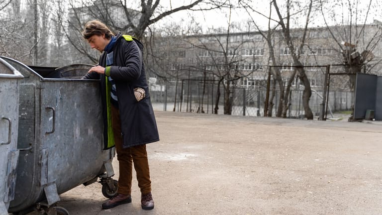 Ein junger Mann schaut in eine Mülltonne: Auf der Suche nach Schätzen scheuen einige nicht davor, in fremde Mülltonnen zu schauen. (Symbolbild)