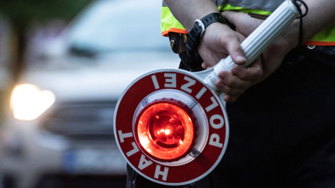 Ein Polizist mit einer Winkerkelle (Symbolfoto): Der Fahrer müsse laut den Beamten nun mit "empfindlichen Konsequenzen" rechnen.