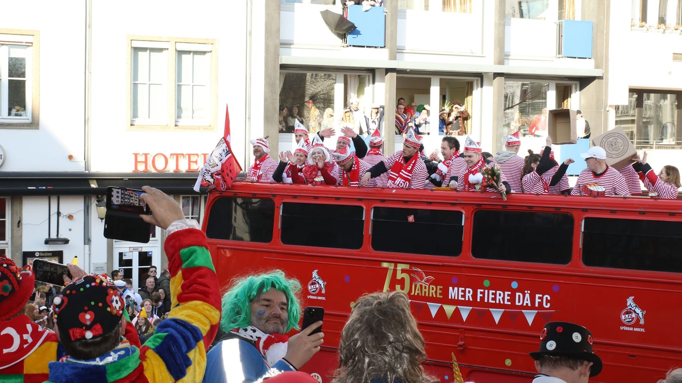 Spieler und Verantwortliche auf dem FC-Bus lassen sich vor der Ehrentribüne der Geißböcke feiern.