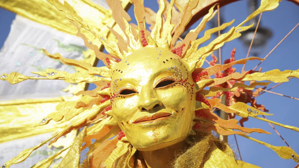 Mensch mit Sonnenmaske (Archivbild): Zu Karneval könnte es ungewöhnlich warm werden.