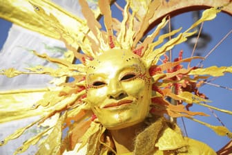 Mensch mit Sonnenmaske (Archivbild): Zu Karneval könnte es ungewöhnlich warm werden.