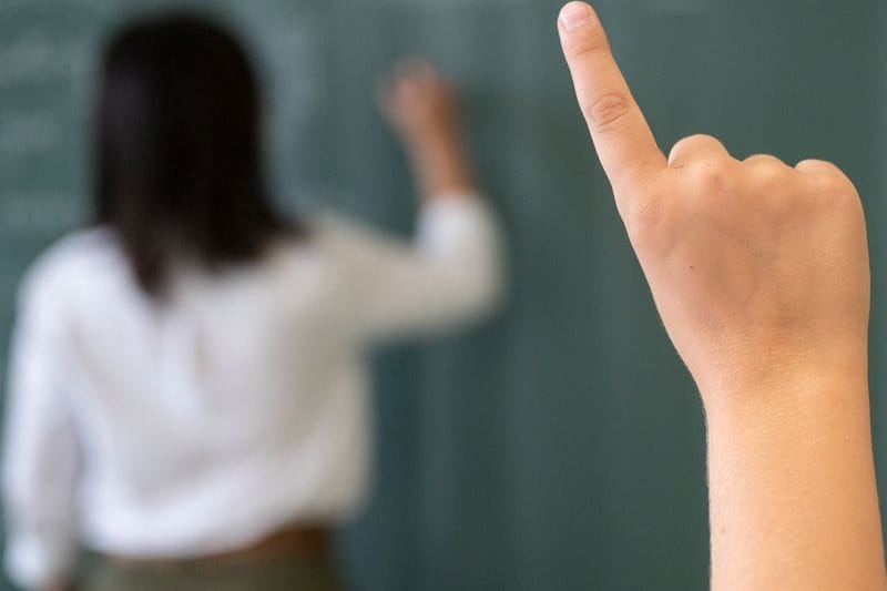 Ein Schüler meldet sich, während die Lehrerin an die Tafel schreibt (Symbolfoto): Besonders Frauen reduzieren häufig ihre Arbeitszeit.