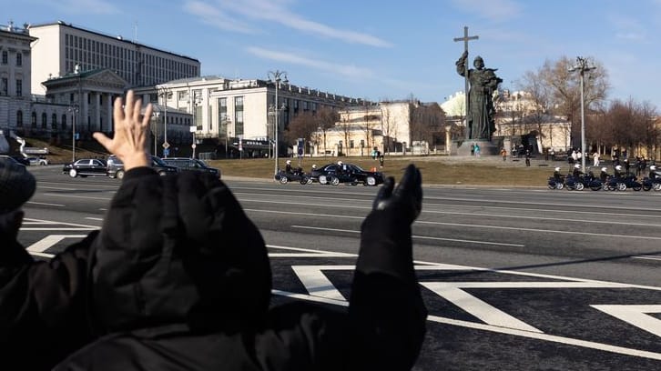 Menschen in Moskau winken der Kolonne des chinesischen Präsidenten Xi Jinping zu.