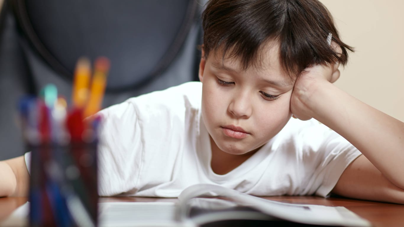 Ein Schüler schaut traurig auf seine Hausaufgaben (Symbolbild): Ärzte schlagen Alarm wegen der aktuell schlechten Versorgung von Kindern und Jugendlichen mit psychischen Problemen.