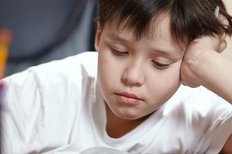Ein Schüler schaut traurig auf seine Hausaufgaben (Symbolbild): Ärzte schlagen Alarm wegen der aktuell schlechten Versorgung von Kindern und Jugendlichen mit psychischen Problemen.