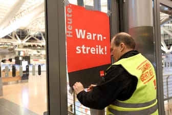 Ein Gewerkschaftsvertreter klebt ein Plakat mit der Aufschrift "Warnstreik!" an die Anzeigetafel vor das leere Terminal 2: Am Flughafen Hamburg sollen die Einschränkungen überschaubar bleiben.