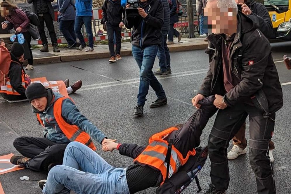 Aktion der "Letzten Generation" in Dresden: Ein Autofahrer zieht einen Klimaaktivisten von der Straße.