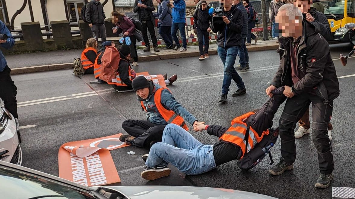 Aktion der "Letzten Generation" in Dresden: Ein Autofahrer zieht einen Klimaaktivisten von der Straße.