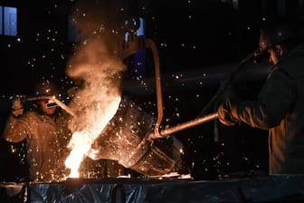 Mitarbeiter gießen geschmolzenes Metall in eine Form in einer Gießerei (Symbolbild): Die steigenden Energiekosten treiben viele Unternehmen an ihre Grenzen.