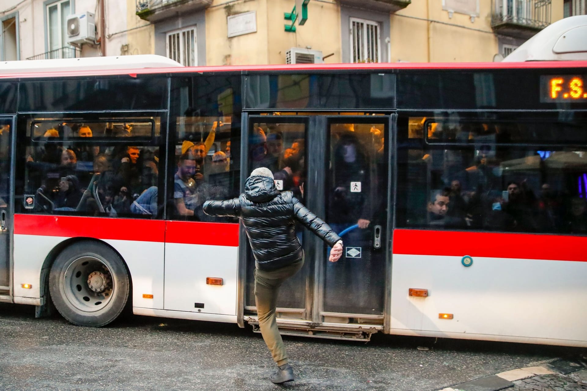 Ein Neapel-Fan tritt nach Zusammenstößen mit der Polizei vor dem Spiel gegen einen Bus: Darin waren Ultras von Eintracht Frankfurt, die weggefahren wurden.