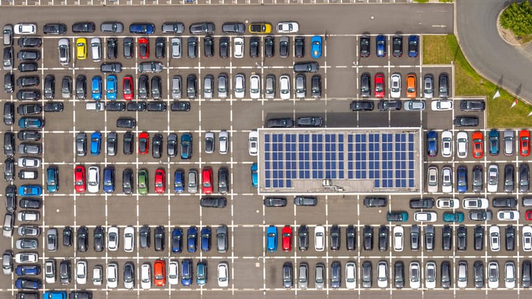Haus mit Solardach auf einem Autohausparkplatz (Symbolfoto): Für Neubauten soll die Regelung erst später gelten.