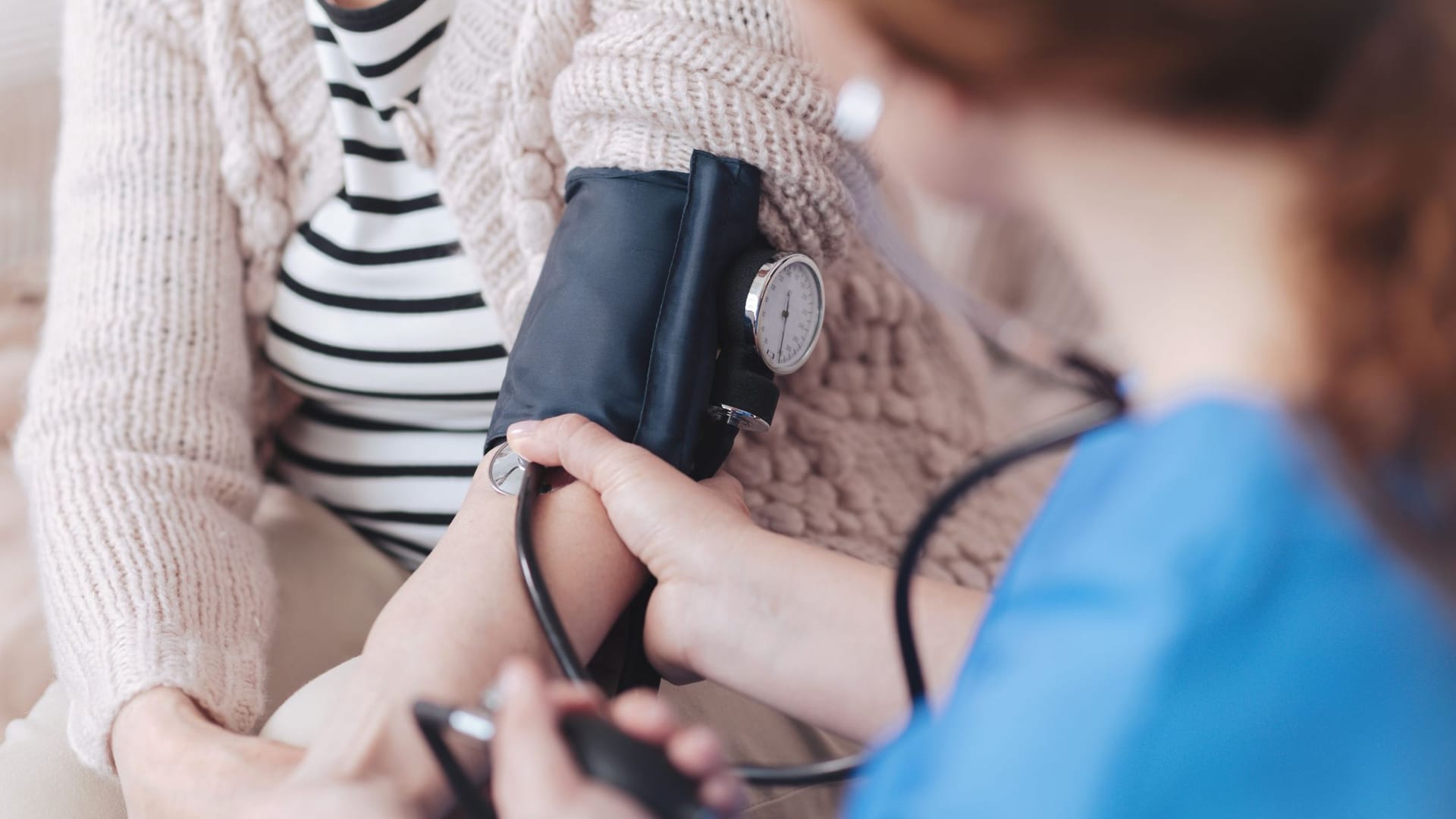 Ärztin misst Blutdruck (Symbolbild): Rentner sind in der Regel in der gesetzlichen Krankenversicherung pflichtversichert.