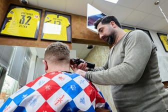 Taner Dogan: Der Friseur schneidet in seinem Salon in einer Netto-Filiale einem Kunden die Haare.
