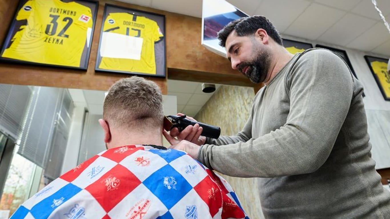Taner Dogan: Der Friseur schneidet in seinem Salon in einer Netto-Filiale einem Kunden die Haare.