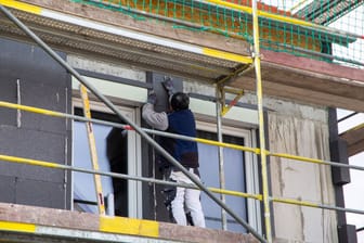 Bauarbeiter isoliert eine Hausfassade: Wohngebäude sollen bis 2030 mindestens die Energieeffizienzklasse «E» und bis 2033 die Energieeffizienzklasse «D» erreichen.