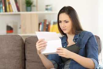 Eine Frau schaut besorgt auf ein Schreiben (Symbolbild): Ihr Vermieter darf nicht nach Belieben die Miete erhöhen.
