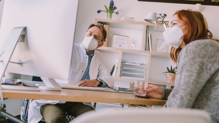 Arzt und Patientin mit FFP2-Masken (Symbolbild): Arztpraxen sind einer der letzten Orte, an denen die Maskenpflicht noch gilt.