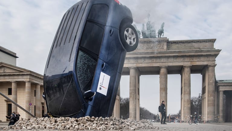 Ein SUV steckt scheinbar im Boden vor dem Brandenburger Tor, aus dem Heckbereich steigt Qualm. Mit dieser Aktion protestieren Umweltschutz-Aktivisten von Greenpeace gegen die Verkehrspolitik der Bundesregierung.