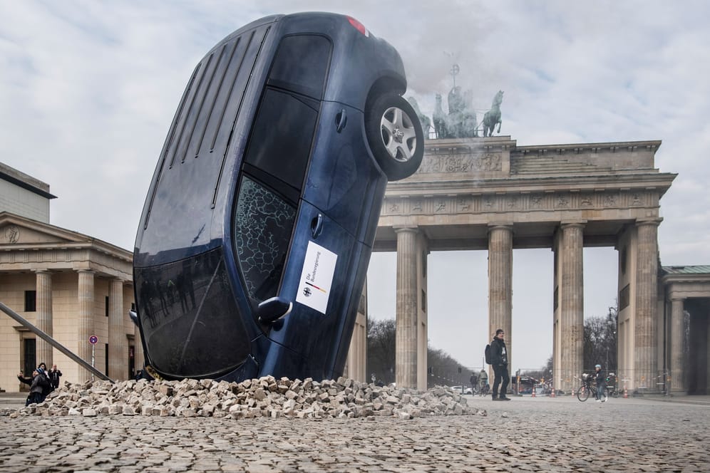 Ein SUV steckt scheinbar im Boden vor dem Brandenburger Tor, aus dem Heckbereich steigt Qualm. Mit dieser Aktion protestieren Umweltschutz-Aktivisten von Greenpeace gegen die Verkehrspolitik der Bundesregierung.