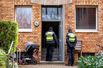 Polizisten stehen im Hamburger Stadtteil Stellingen vor einem Mehrfamilienhaus. Eine Hundertjährige soll dort von ihrem Enkel getötet worden sein.