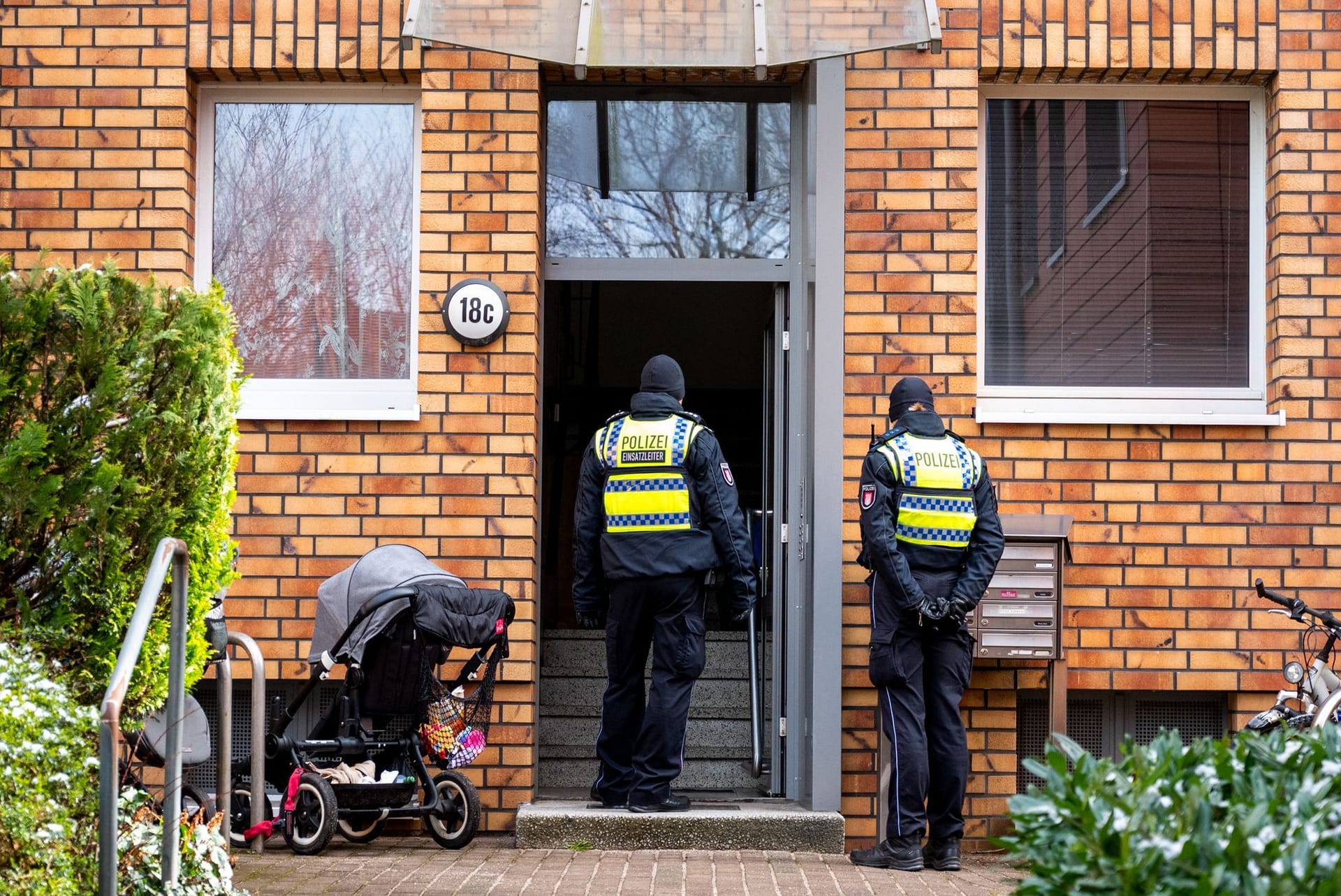 Polizisten stehen im Hamburger Stadtteil Stellingen vor einem Mehrfamilienhaus. Eine Hundertjährige soll dort von ihrem Enkel getötet worden sein.